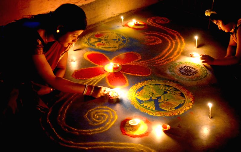A woman and her child busy making 'Rangoli' on the eve of Diwali in Kolkata, on Oct 18, 2017.